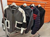 Four men's jackets hanging on a rack showing various styles and colors.