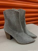 Side view of the sparkling silver ankle boots showing pointed toes and wooden block heels.