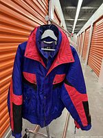 Front view of vintage snow jacket showing color block design in purple, red, and black with button closures