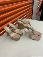 Four pairs of nude Steve Madden women's shoes and wedges displayed on table, showing platform heels with clear straps and cork wedge heels.