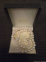 Necklace and earrings set displayed in a box with '14 karat gold Cultured Pearl' inscription inside the lid.