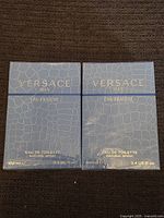 Two boxed bottles of Versace Man Eau Fraîche Eau de Toilette in sealed blue packaging with reptile skin texture.