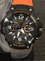 Close up front view of Casio chronograph watch with orange band showing dial details and markings.