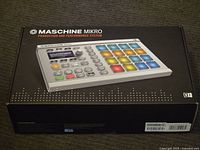 Closed original box showing Native Instruments Maschine Mikro production and performance system with image of controller and branding.