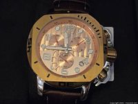 Close up of watch face showing rose gold dial, chronograph sub-dials, and gold-tone bezel.