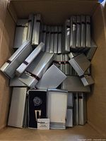 Box filled with multiple white boxes containing Barlow branded golf ball markers.