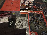 Overview of various Static-X related items including signed fan club packet, stickers, guitar pick, concert ticket, and printed materials.
