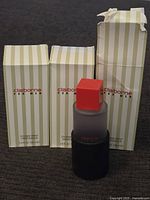 Three Liz Claiborne For Men cologne spray boxes with one bottle in front. Boxes have vertical pale green and white stripes, some wear visible.