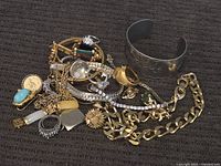Overview of pile showing cuff bracelet, chains, brooches and rings