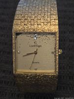 Front view of the rectangular gold-tone Lord Elgin watch face showing the dial and logo with signs of wear.