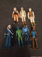 Seven vintage Star Wars action figures laid out on dark fabric surface showing front details.