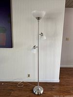 Full view of the 360 Lighting Ellery modern tree torchiere floor lamp standing on wooden floor in front of white paneled wall with power cord visible on floor.