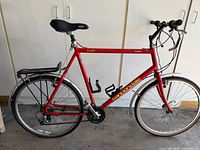 Side view of red Cannondale M300 bicycle showing full frame, saddle, rear rack, tires, and pedals.
