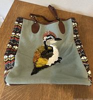 Full view of the Jasper And Jeera Anthropologie tote bag with beaded sequin bird design on front and patterned side panels, placed on wooden table.