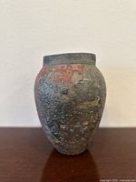 Front angled view showing textured surface with gray and reddish hues, oval shape