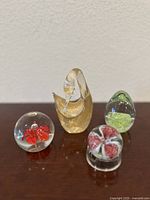Set of four vintage crystal paperweights on a wooden surface against a white wall, showing all items together
