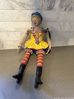 Full view of the clay sculpture sitting, showing detailed costume and painted facial features.