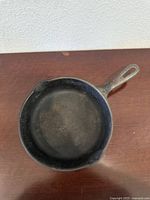Top view of vintage cast iron pan showing inside surface and two small pouring spouts on each side of the pan.