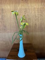 Yellow seed bead daffodil flowers with green beaded stems and leaves in a light blue textured vase, front view