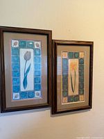 Pair of framed hand-painted floral tile artworks showing overall view with both panels mounted on wall.