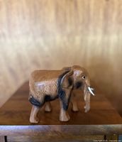 Side view of vintage hand carved wooden elephant figurine showing detailed carving and painted features