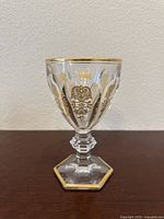 Side angle view of the vintage Harcourt Empire wine goblet showing gold decoration and faceted stem and base.