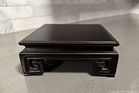 Front view of vintage Oriental rosewood square stand showing carved geometric front legs and smooth top surface.