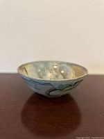 Side view showing the exterior glazing and shape of the bowl on a wooden surface with cream wall background.