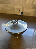 Side angle of the silver candy trinket box showcasing the decorative berry and leaf handle on the lid and overall shape.