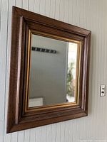 Front view of the vintage wooden framed mirror showing its rectangular shape and gold inner trim.