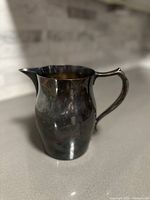 Front angle view of the silverplate water pitcher with a rounded body and spout.