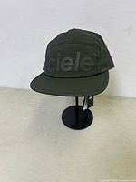 Front view of dark olive green Ciele Athletics GOCap running hat on stand showing reflective logo.