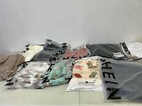 15 pieces of new clothing items, packaged in clear bags with SHEIN branding and some with leisurewear cartoon prints.