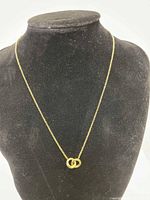 Full view of the gold-tone interlocking links necklace displayed on a black jewelry stand.