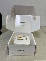 Open white Kloudy jewelry box displaying the ring and bracelet inside on a white cushion.