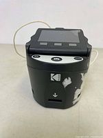 Front angled view of black Kodak Scanza scanner showing worn side with peeling and the screen without power.