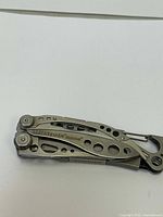 Folded view of the LEATHERMAN Skeletool multitool showing the metal body and carabiner clip.