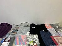 Various new kids clothing pieces spread out showing brand bags and different items in the lot.