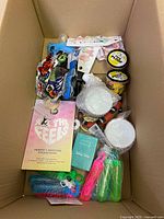 Photo showing the box with various craft and kids items including sticker book, Play-Doh tubs, bubble wands, yarn, and other small craft materials.