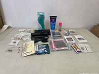 Photo showing various women's beauty and accessory items arranged on a surface, including false nails, cosmetics, sunglasses in a case, and grooming tools.