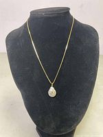 Full view of necklace displayed on black bust showing the chain and opal evil eye pendant