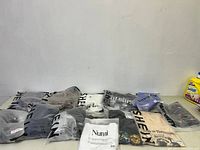 Photo showing 15 pieces of new clothing, mostly Shein brand, all in individual packaging with visible logos and barcodes