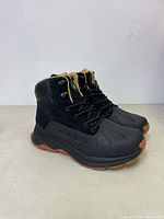 Side profile of the black NORTIV 8 women's hiking boots showing their laces, the black upper with padded collar, and the brown rubber outsole.