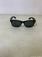 Front view of black Ray-Ban New Wayfarer sunglasses on a surface.