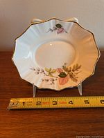 Top view of a white bone china dish showing acorn and leaf pattern with gold edge, measuring approximately 6 inches in diameter.