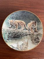 Front view of the decorative plate showing two cougar cubs on a log by water.