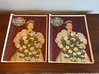 Two copies of the Overseas Daily Mirror Coronation Souvenir issue N. 2098 from June 4, 1953, showing color cover image of Queen Elizabeth II in coronation attire holding bouquet of flowers.