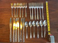 Top view of the full cutlery set for 6 showing forks, knives, and spoons placed in rows, with measuring tape for size reference.