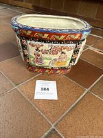 Front and side views of the ceramic planter showing hand-painted panels with traditional Chinese women, peony flowers, and birds, capturing the Victorian-style decoration.