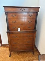 Front view of the antique wooden dresser showing eight drawers with metal handles and carved vertical columns on the sides.